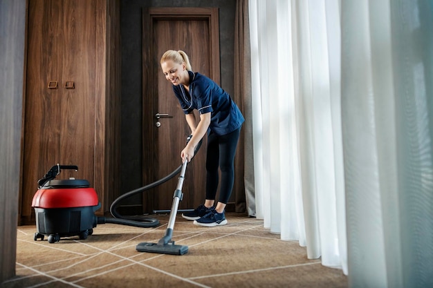 Una cameriera sta usando l'aspirapolvere per pulire la camera d'albergo