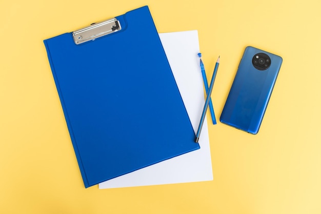 Una cancelleria blu impostata come modello con un posto da copiare su uno sfondo giallo con un telefono blu