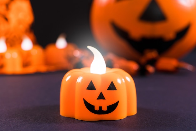 Una candela a forma di zucca si illumina su uno sfondo scuro.