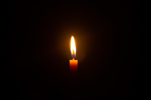 Una candela accesa che brucia brillantemente sullo sfondo nero