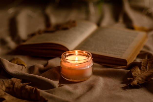 Una candela accesa su un tavolo di legno davanti a un libro a mezz'asta. Apprendimento. Studiare la Bibbia