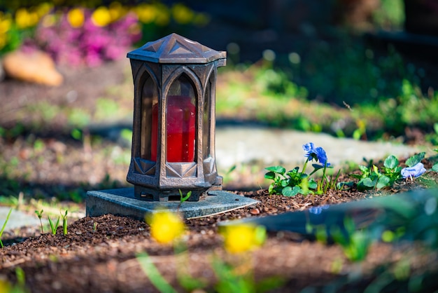 Una candela rossa sulle pietre tombali con fiori