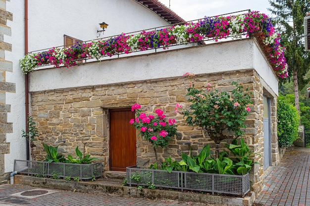 Una casa con un muro di mattoni e fiori sul tetto.