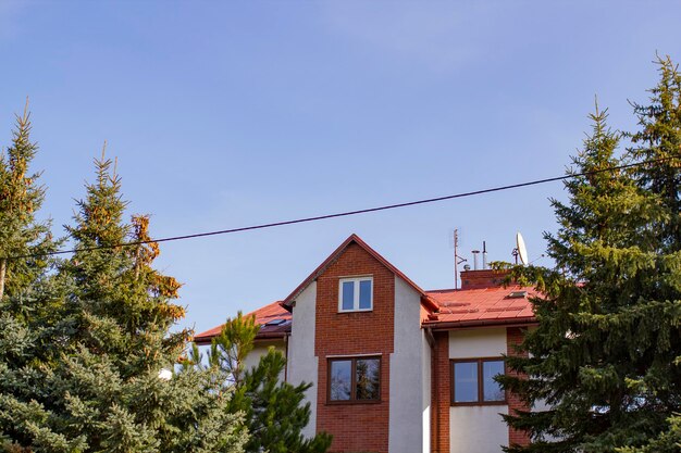 Una casa con un tetto rosso e finestre e alberi verdi vicino