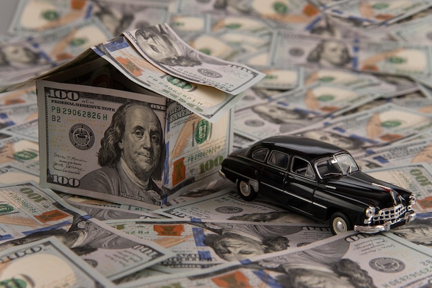 una casa di banconote da un dollaro e un'auto su banconote sparse