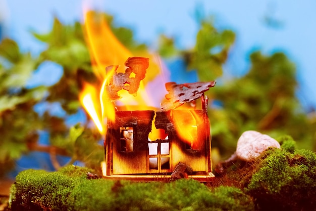 Una casa di legno giocattolo sta bruciando in natura Concetto antincendio Sicurezza antincendio