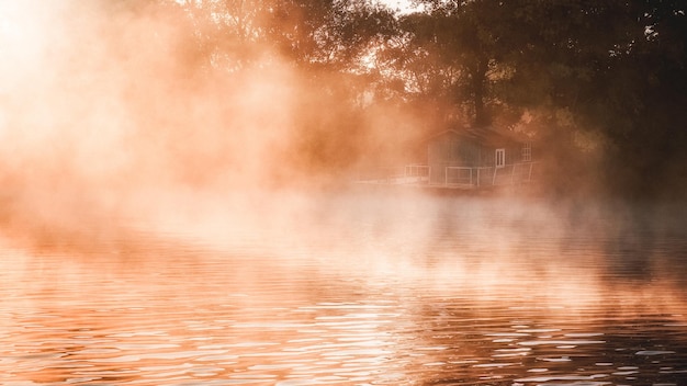 Una casa sul molo nella nebbia mattutina e nella luce del sole