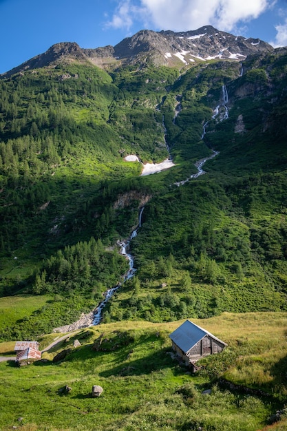 Una cascata che scende dalla montagna nella valle è una piccola capanna