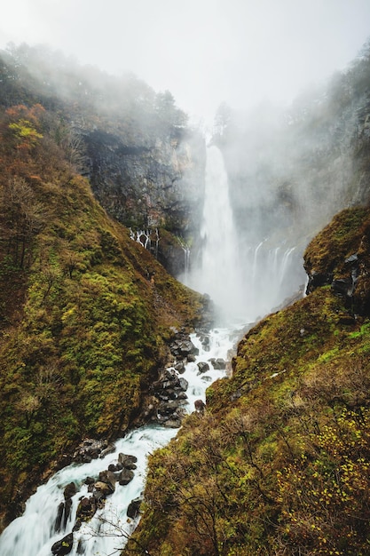 Una cascata in montagna con muschio verde e una montagna verde sullo sfondo