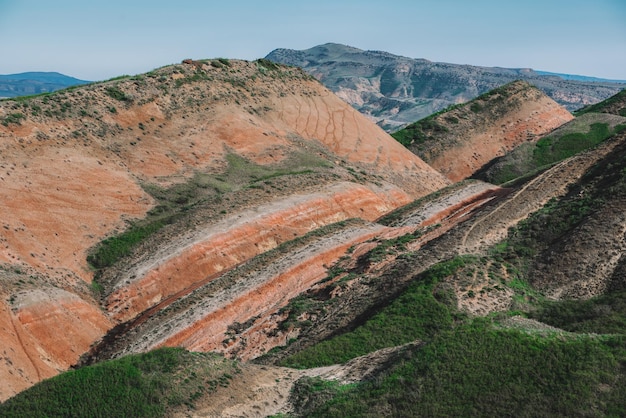 Una catena montuosa con una collina rossa e verde e un cielo blu