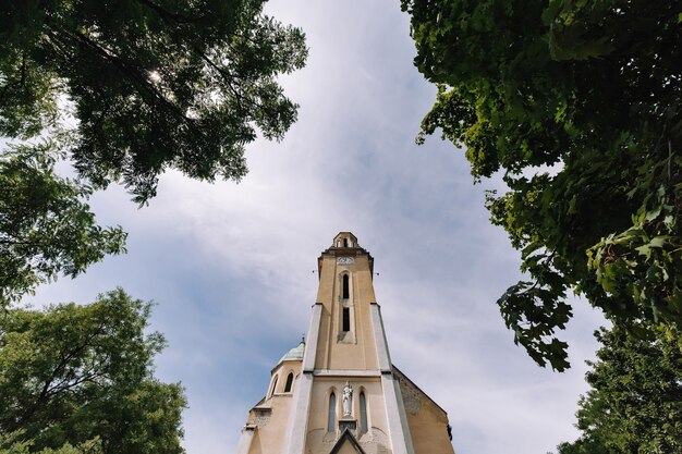 Una chiesa a Budapest, in Ungheria, su uno sfondo di nuvole e una cornice con alberi.