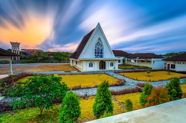 Una chiesa in mezzo a un campo alberato e un cielo con nuvole