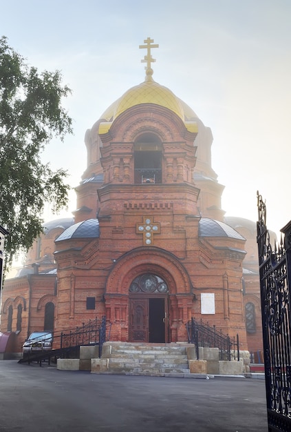 Una chiesa ortodossa con una cupola dorata in stile architettonico russo-bizantino nella nebbia mattutina. Siberia, Russia