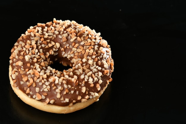 Una ciambella glassata al cioccolato con glassa al cioccolato e spruzza su un tavolo nero.