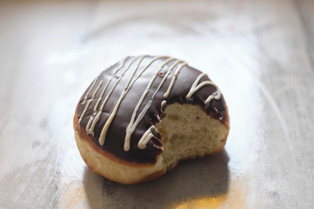 Una ciambella mezza mangiata con glassa bianca e glassa al cioccolato.