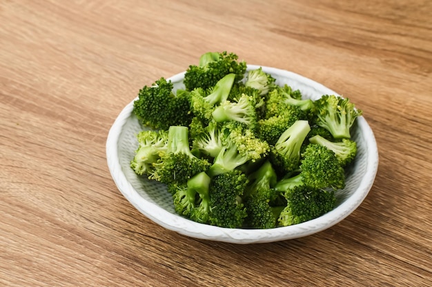 Una ciotola di broccoli crudi freschi pronti da cucinare servita su fondo in legno Immagine di messa a fuoco selezionata