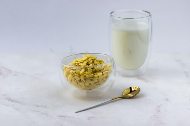 Una ciotola di cereali per la colazione e un bicchiere di latte su un tavolo di marmo bianco Fiocchi di mais istantanei