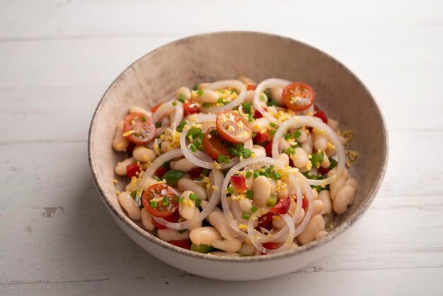 Una ciotola di fagioli bianchi con cipolle pomodori e coriandolo