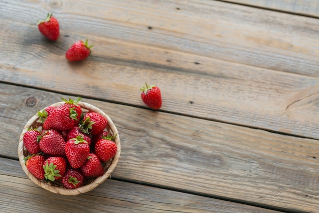 Una ciotola di fragole rosse succose sul tavolo in legno rustico