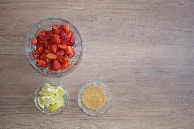 Una ciotola di fragole un limone e zucchero di canna Gli ingredienti di una limonata