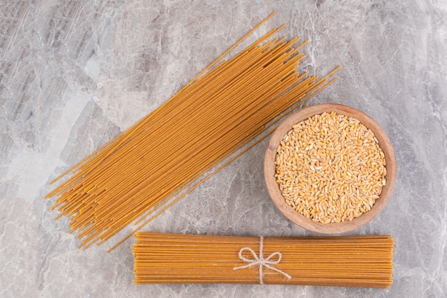 Una ciotola di grano e spaghetti, sul marmo.