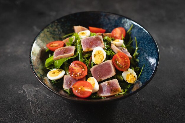 Una ciotola di insalata di tonno con pomodori e spinaci.