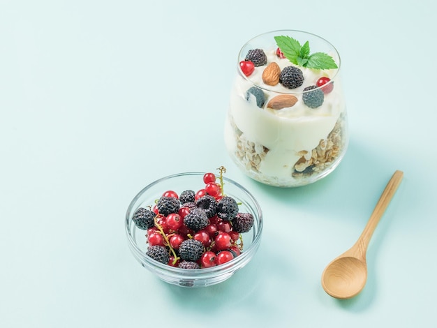 Una ciotola di lamponi e ribes e un bicchiere di yogurt su sfondo blu