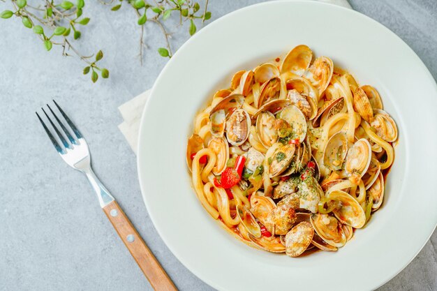 Una ciotola di pasta ai frutti di mare con accanto una forchetta