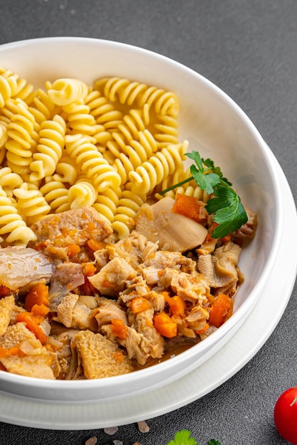 Una ciotola di pasta con pollo e verdure