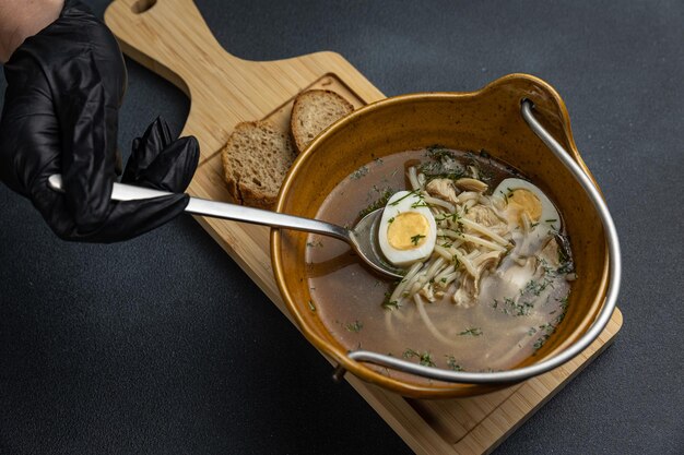 Una ciotola di ramen con dentro un cucchiaio e una fetta di pane a parte.