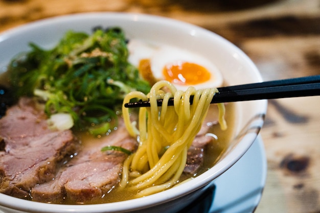 Una ciotola di ramen con le bacchette e una ciotola di noodles.