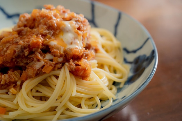 Una ciotola di spaghetti con salsa e formaggio in cima.