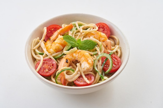 Una ciotola di tagliatelle di gamberi e zucchine con pomodoro e basilico