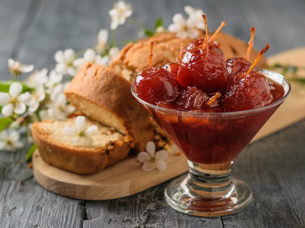 Una ciotola di vetro di intera marmellata di mele e una torta fresca su un tavolo di legno. Dolci fatti in casa secondo antiche ricette.