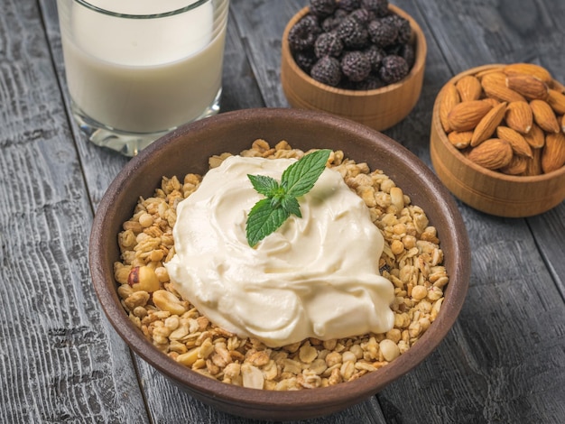 Una ciotola di yogurt muesli e foglie di menta su un tavolo di legno