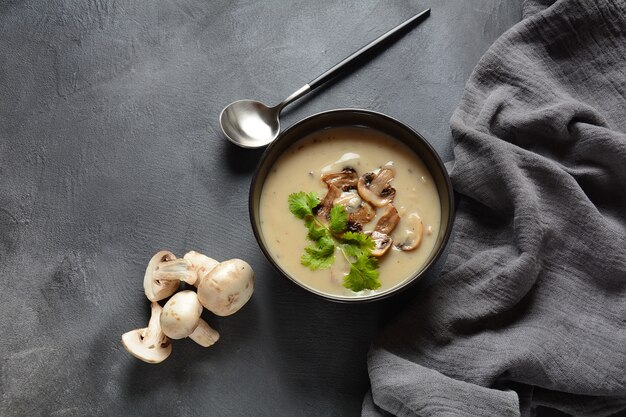 Una ciotola di zuppa di crema di funghi con funghi prataioli fritti e prezzemolo fresco.