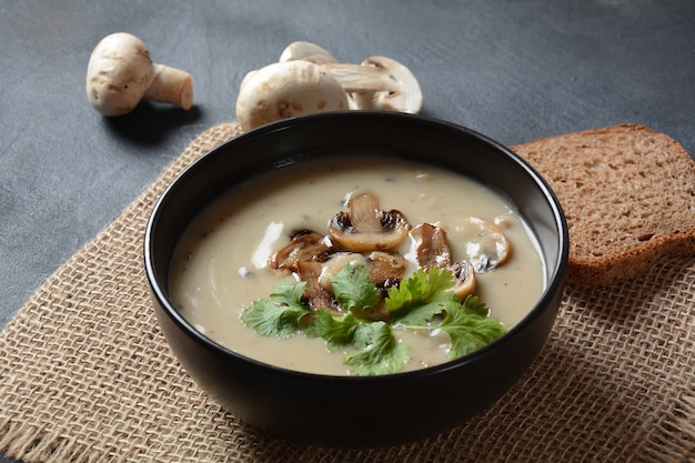 Una ciotola di zuppa di crema di funghi con funghi prataioli fritti e prezzemolo fresco.