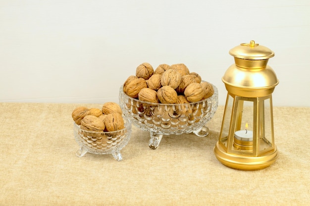 Una ciotola dorata di noci si trova accanto a una lanterna dorata e una piccola ciotola di noci.