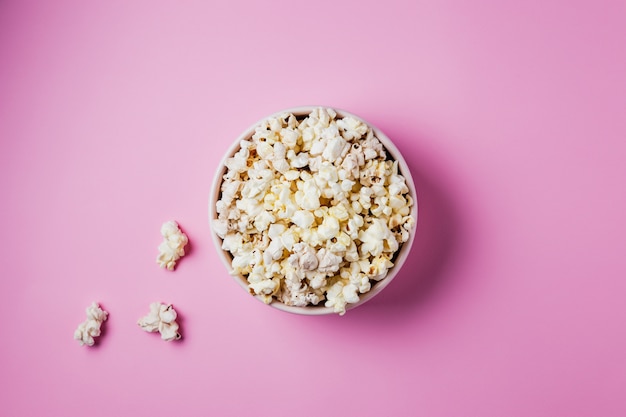 Una ciotola rosa di popcorn sulla superficie rosa