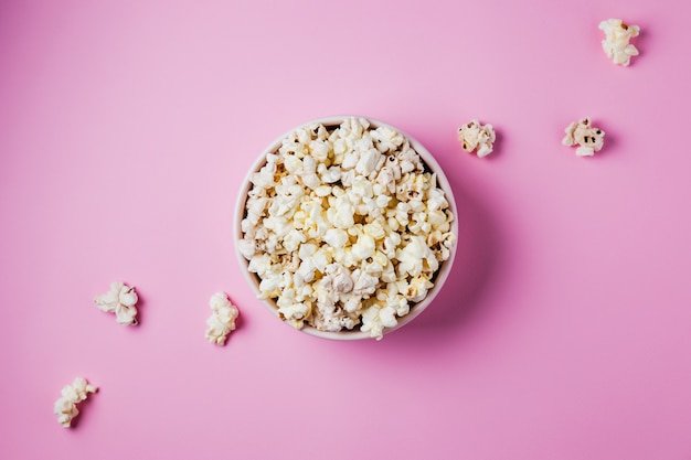 Una ciotola rosa di popcorn sulla superficie rosa