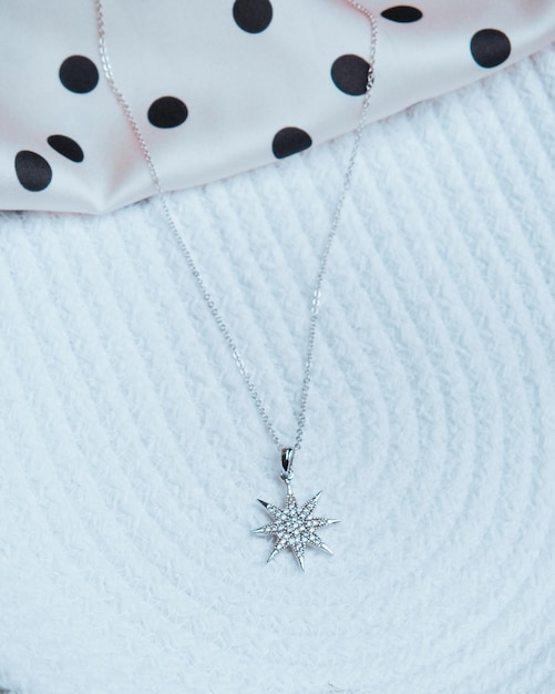 Una collana con un diamante e un diamante su di essa è su una superficie bianca.