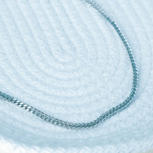 una collana d'argento è adagiata su una coperta bianca con una catena d'argento.