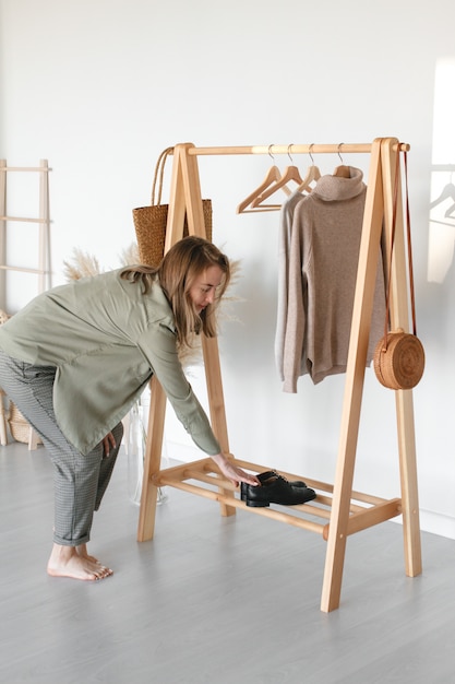 Una collezione di abiti, nei toni del beige, appesi a una gruccia nel camerino. Materiale naturale. La donna sceglie abiti eleganti.