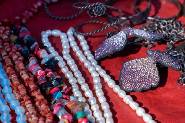 Una collezione di collane e collane è esposta su un tavolo rosso.