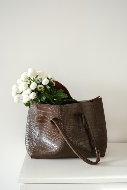 Una composizione chic di una borsa di stilista con fiori freschi foto di alta qualità