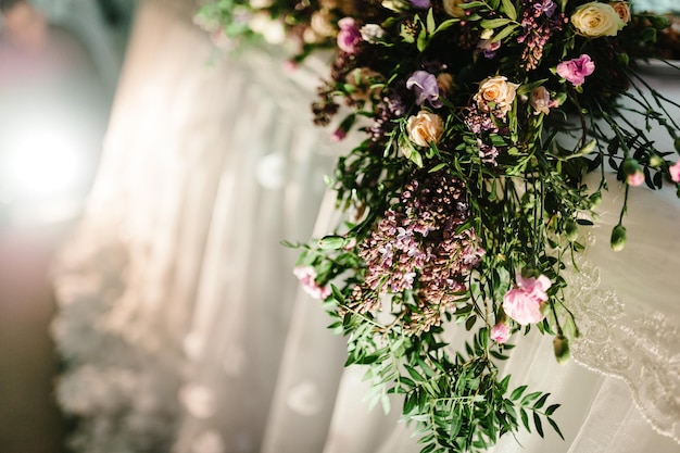 Una composizione di fiori e verde è su un tavolo festivo nella sala del banchetto nuziale Primo piano