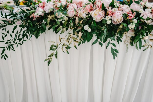 Una composizione di fiori e verde è su un tavolo festivo nella sala del banchetto nuziale Primo piano