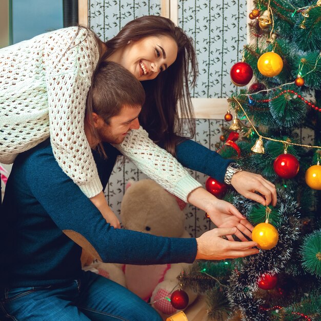 Una coppia adorabile decora l'albero di Natale. Capodanno.