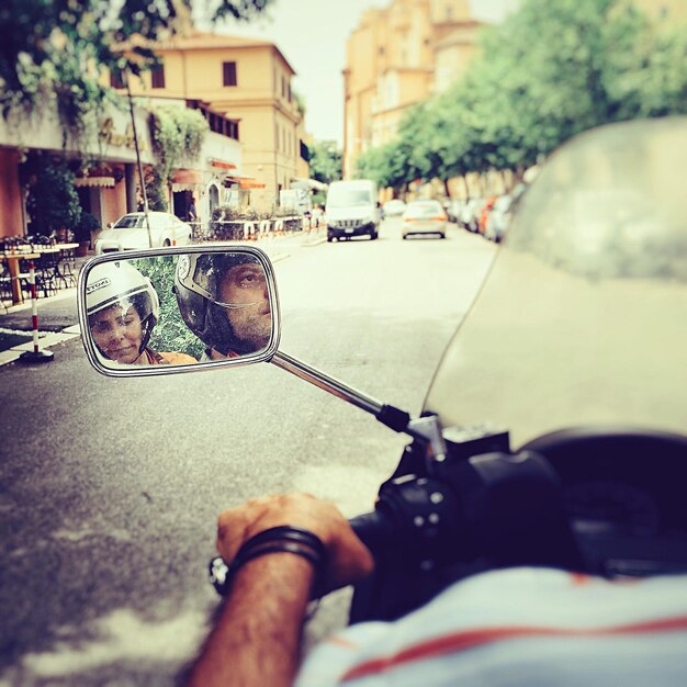 Una coppia adulta riflette sullo specchio laterale di una motocicletta