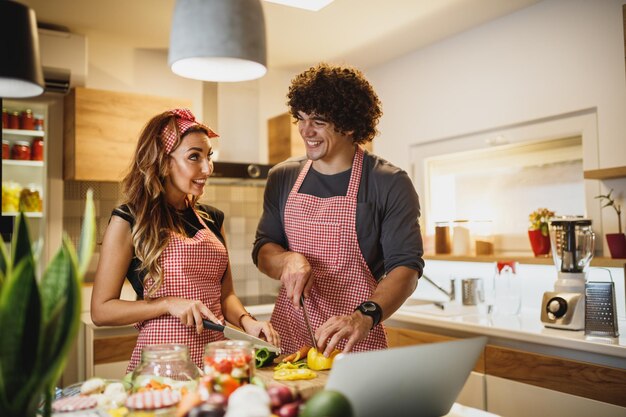 Una coppia allegra che cucina insieme in cucina.